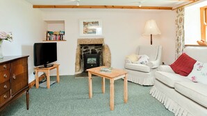 Ein Wohnzimmer mit Kamin, Fernseher, Sofa und Lampe.