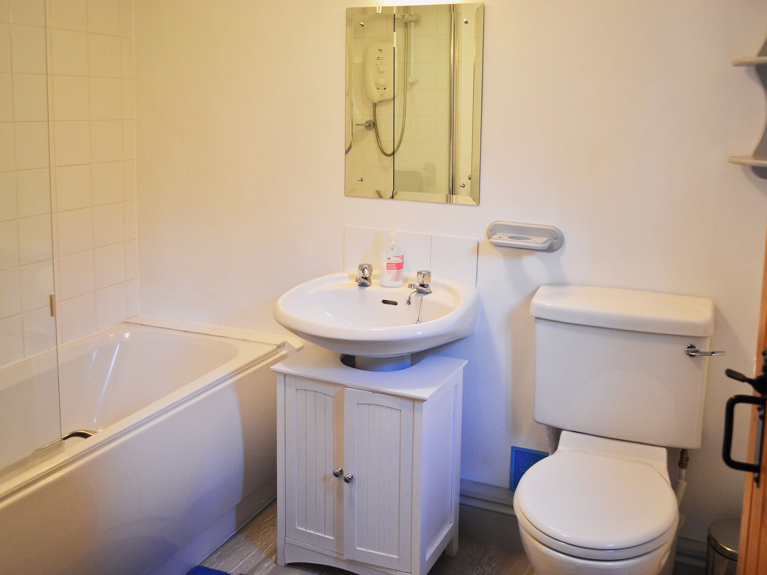 Une salle de bain avec une baignoire, un lavabo, des toilettes et un meuble de rangement.