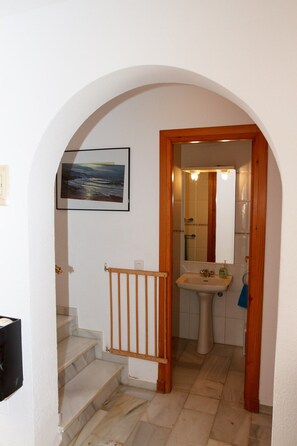 A staircase leading to a bathroom with a sink and mirror.