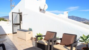 A rooftop terrace with two wicker chairs, a small table, a radiator, and a satellite dish. - Cerros del Águila - charming townhouse (Mijas Costa)