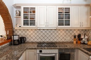 A kitchen with white cabinets, a granite countertop, a coffee maker, and a toaster.