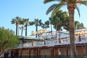 Een gebouw met een bord waarop 'BAR REST CLUB CERROS DEL AGUILA' staat, en een overdekt terras met een pergola.