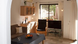 A living room with a dining table, a TV, and a kitchen area visible through an archway. - Cerros del Águila - charming townhouse (Mijas Costa)