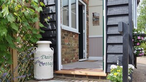 A cottage entrance with a white ceramic pot labeled 'Dairy Cottage,' a wooden bench, and a brick pathway leading to the door. - 1 bedroom accommodation in Pembury, near Tunbridge Wells (Pembury, near Tunbridge Wells)