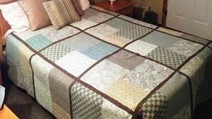 Un dormitorio con una cama grande, una mesita de noche con lámpara, un cuadro en la pared y una puerta.