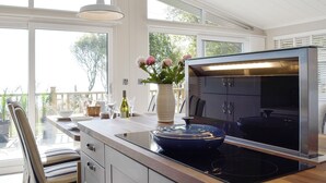 A modern kitchen with a large island, a built-in oven, and a view of the outdoors. - 2 bedroom accommodation in Corton, near Lowestoft (Corton, near Lowestoft)