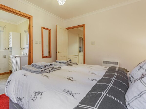 A bedroom with a bed, two mirrors, a radiator, and a window.