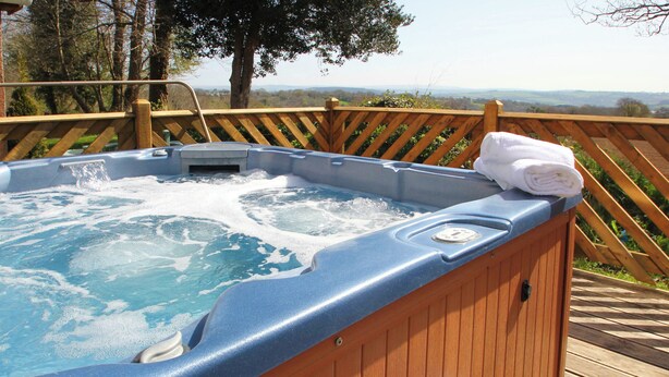Une terrasse en bois avec un jacuzzi, une paire de tongs et une serviette enroulée.