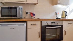 A compact kitchen with a microwave, a small oven, a dishwasher, and a kettle on the counter. - 1 bedroom accommodation in Ventnor (Ventnor)