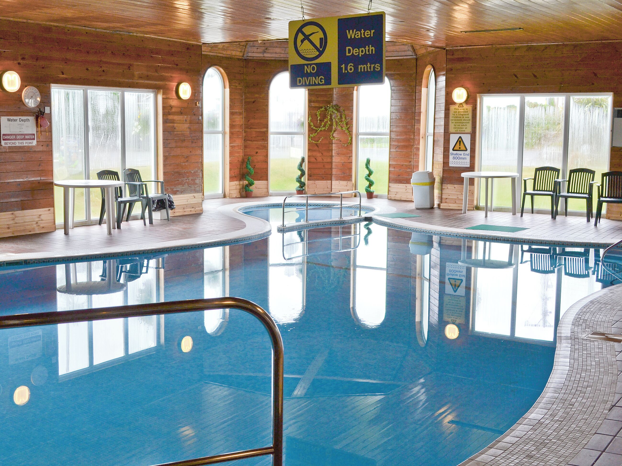 An indoor swimming pool with a sign indicating a water depth of 1.6 meters and a no-diving warning.