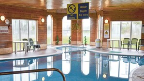 En indendørs swimmingpool med skilt, der angiver en vanddybde på 1,6 meter og forbyder dykning.