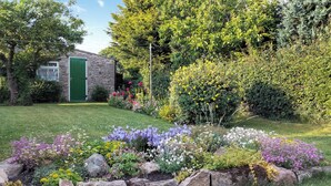 A garden with a stone building, a green door, and various flowering plants. - 1 bedroom accommodation in Caldwell, near Richmond (Caldwell, near Richmond)