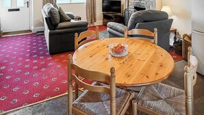 A living room with a round wooden table, two sofas, a television, and a fireplace. - 1 bedroom accommodation in Caldwell, near Richmond (Caldwell, near Richmond)