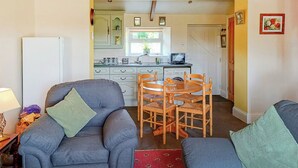 A living room with two grey sofas, a red patterned rug, and a wooden dining table with chairs. - 1 bedroom accommodation in Caldwell, near Richmond (Caldwell, near Richmond)