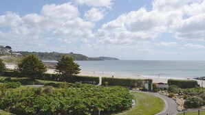 Un paisaje costero con playa, un camino y vegetación.