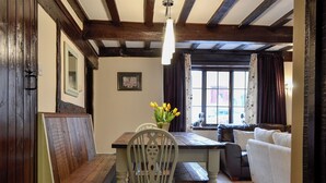 Una habitación acogedora con un banco de madera, una mesa con un florero y una silla blanca, además de un sofá.