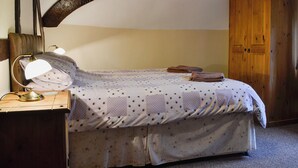 Un dormitorio con cama, escritorio con lámpara y armario.