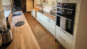 Una cocina moderna con encimera de madera, electrodomésticos de acero inoxidable y armarios de tonos claros.