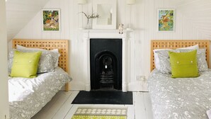 A room with two beds, a fireplace, and a patterned rug. - 3 bedroom accommodation in Lothmore, Helmsdale (Lothmore, Helmsdale)