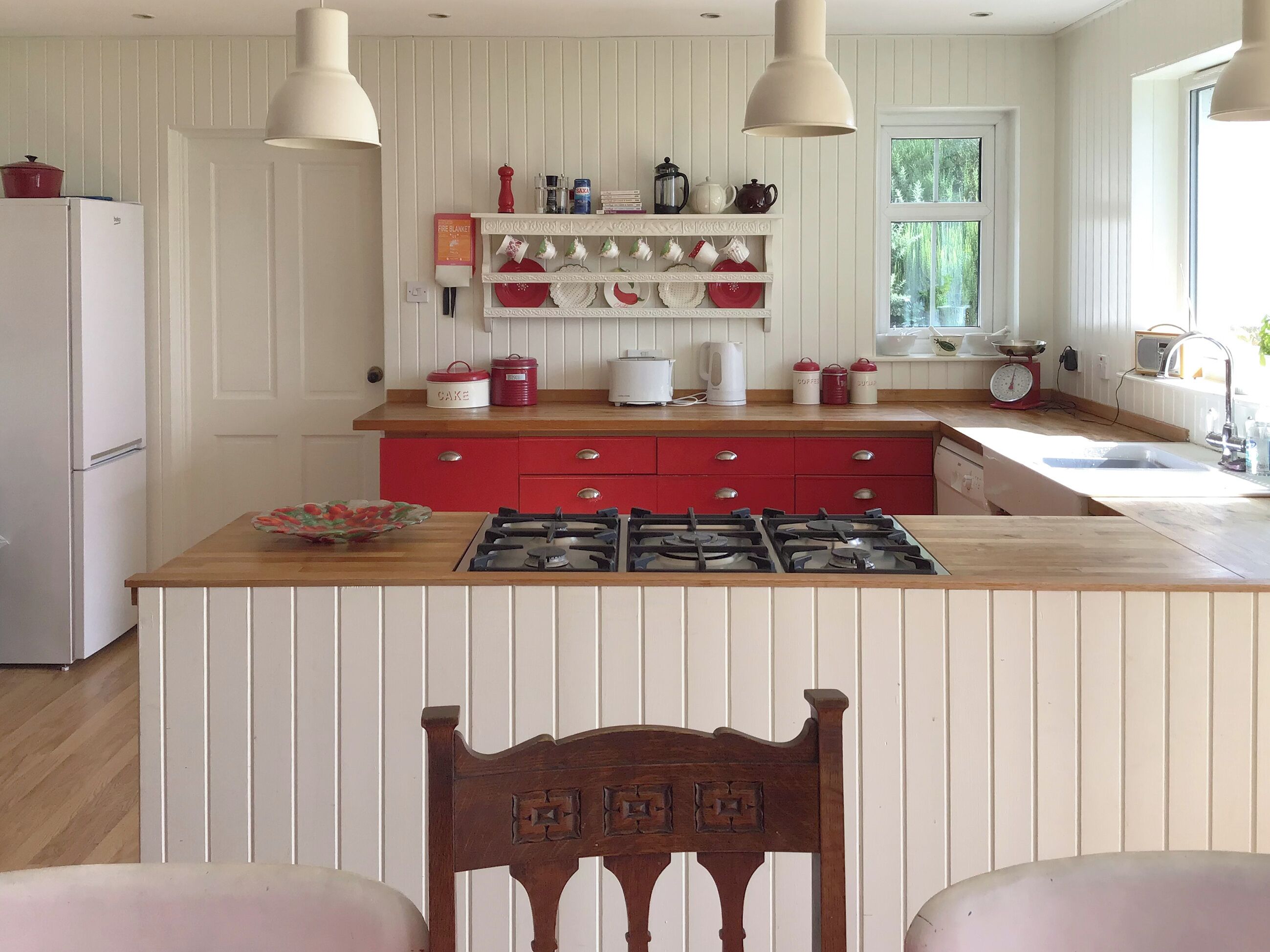 A kitchen with a central island, wooden cabinets, and a red countertop.
