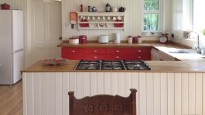 A kitchen with a central island, wooden cabinets, and a red countertop. - 3 bedroom accommodation in Lothmore, Helmsdale (Lothmore, Helmsdale)