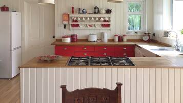 A kitchen with a central island, wooden cabinets, and a red countertop.
