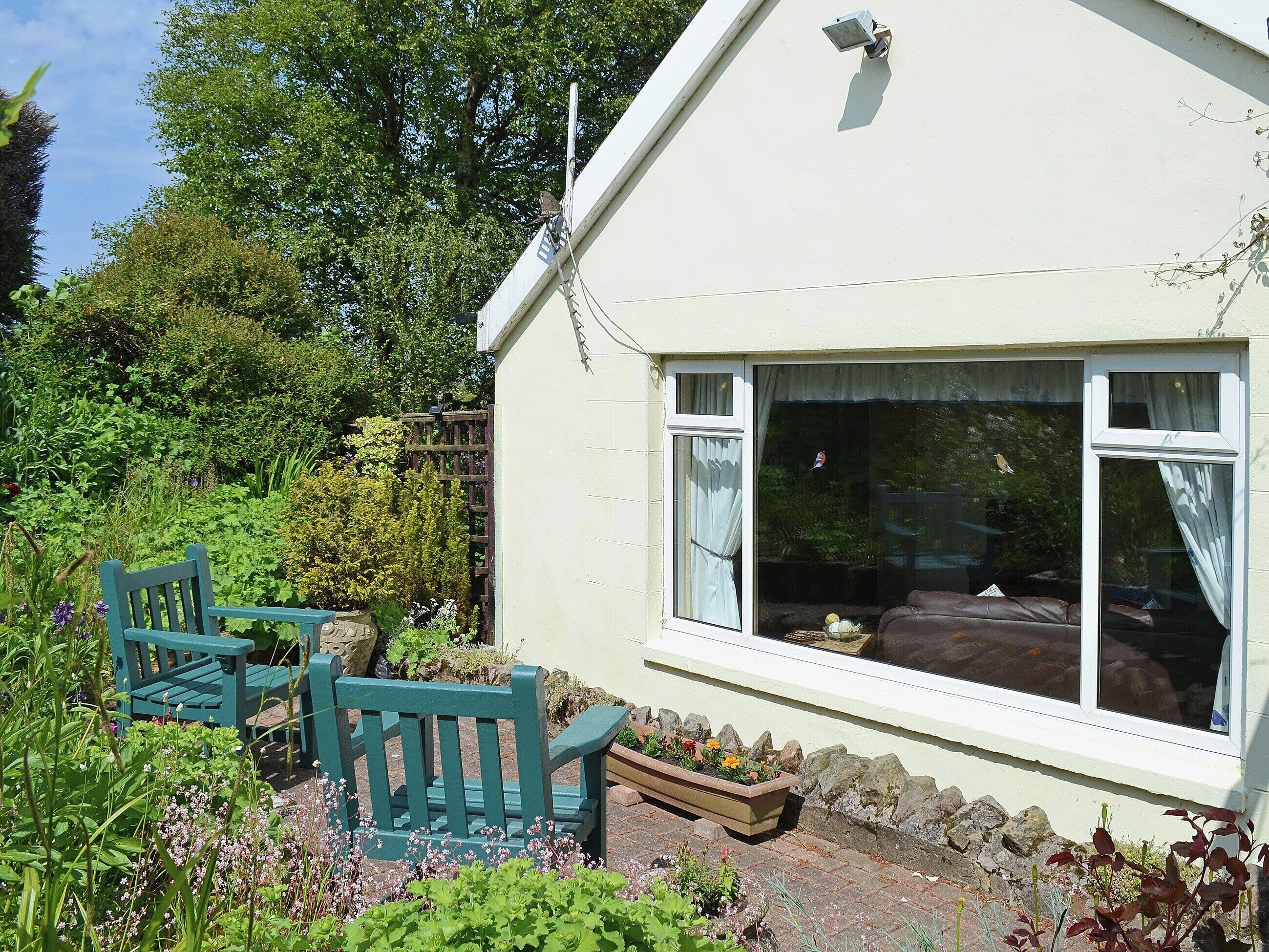 A house with a garden, a bench, and a window.