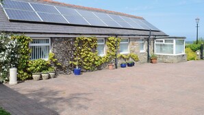Una casa de piedra con techo de tejas y paneles solares.