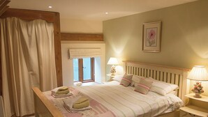 Een slaapkamer met een bed, nachtkastjes, een raam en een gordijn.