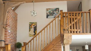 Een houten trap met een ster-vormige lamp, een schilderij van een stel en een bakstenen muur.