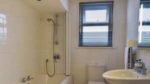 A bathroom with a bathtub, toilet, and sink. - 2 bedroom accommodation in Southport (Southport)