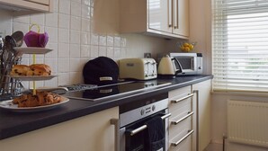 A modern kitchen with white cabinets, a black countertop, a toaster, a microwave, and a sink. - 2 bedroom accommodation in Southport (Southport)