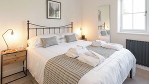 A neatly made bed with pillows, a bedside lamp, a framed picture on the wall, and a window with a view. - The Old Meeting Hall (King&rsquo;s Somborne, near Winchester)