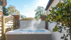A hot tub with steam, a wooden deck, and a brick wall. - The Old Meeting Hall (King&rsquo;s Somborne, near Winchester)