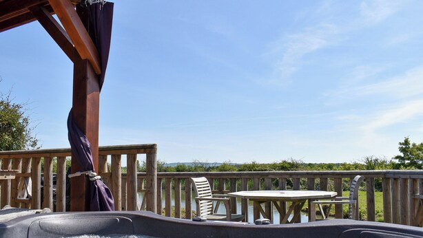 Un bain à remous avec une terrasse en bois et du mobilier d’extérieur.