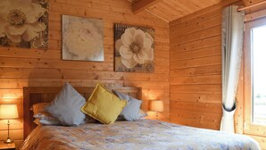 Une chambre dans une cabane en bois, avec un lit, des oreillers et des œuvres d’art murales.