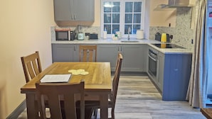 A compact kitchen with a dining table, chairs, and basic appliances. - 2 bedroom accommodation in Penygroes, near Caernarfon (Penygroes, near Caernarfon)