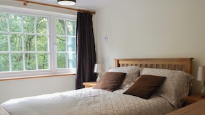 A bedroom with a large window, a wooden headboard, two bedside lamps, and a bed with patterned bedding. - 2 bedroom accommodation in Penygroes, near Caernarfon (Penygroes, near Caernarfon)
