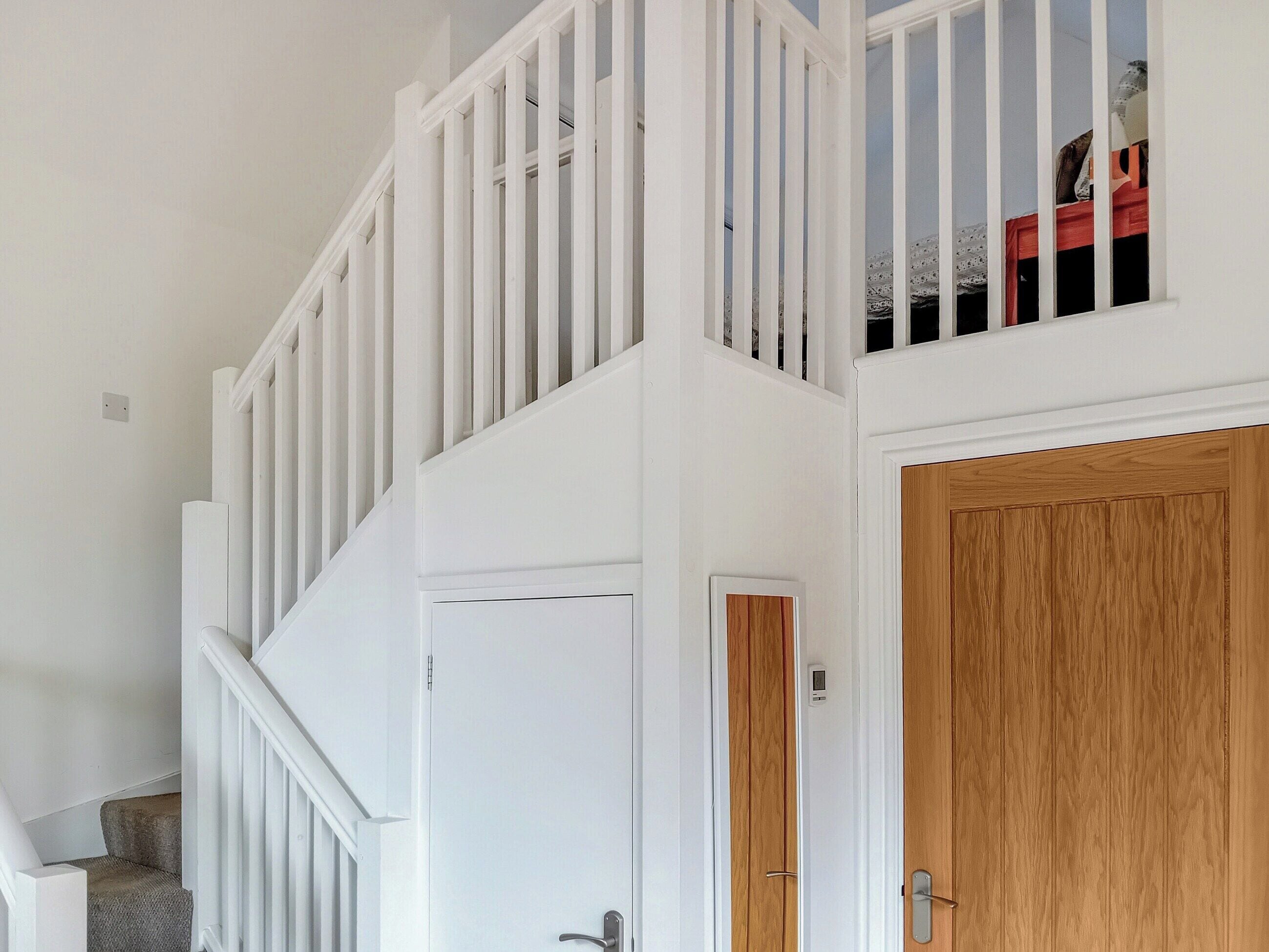 A staircase with white railings and a wooden door at the bottom.