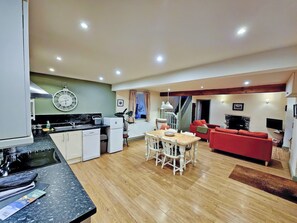Eine moderne Küche mit Essbereich, einem roten Sofa und einer Treppe, die nach oben führt.