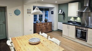 Una cocina moderna con armarios de madera, una mesa de comedor con sillas y una lámpara colgante.