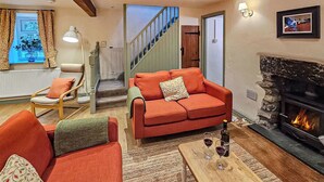 Una sala de estar con chimenea, una escalera y vistas al exterior.