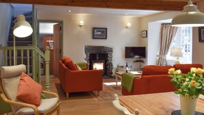 Un salón acogedor con chimenea, muebles de madera y una escalera que sube a un nivel superior.
