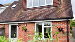 A two-story brick house with a tiled roof, white-framed windows, and a visible chimney. - 1 bedroom accommodation in Rye (Rye)