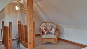 A cozy room with a wooden staircase, a wicker armchair with floral cushions, and a radiator on the wall. - 1 bedroom accommodation in Rye (Rye)