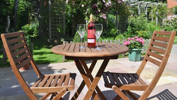 Ein Holztisch mit zwei Stühlen in einem Garten.