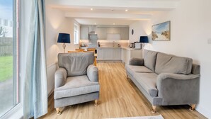 Una sala de estar moderna con un sofá, un sillón y un comedor con mesa y sillas.