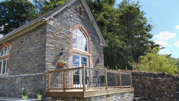 A stone house with a wooden balcony, a window with a white frame, and a stone wall. - 2 bedroom accommodation in St Neot, near Liskeard (St Neot, near Liskeard)