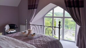 A bedroom with a large bed, a chair, and a view of greenery outside. - 2 bedroom accommodation in St Neot, near Liskeard (St Neot, near Liskeard)