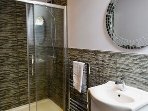 Une salle de bain moderne avec une douche à parois de verre, un lavabo blanc et un miroir en mosaïque.